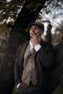 1920 'lerden kalma düz şapkalı bir İngiliz gangsterin portresi. Sokakta sigara içiyor...