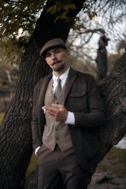 1920 'lerden kalma düz şapkalı bir İngiliz gangsterin portresi. Sokakta sigara içiyor...