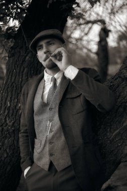 1920 'lerden kalma düz şapkalı bir İngiliz gangsterin portresi. Sokakta sigara içiyor...
