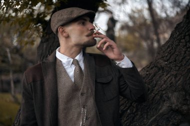 1920 'lerden kalma düz şapkalı bir İngiliz gangsterin portresi. Sokakta sigara içiyor...