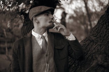 1920 'lerden kalma düz şapkalı bir İngiliz gangsterin portresi. Sokakta sigara içiyor...