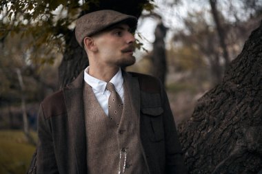 1920 'lerden kalma düz şapkalı bir İngiliz gangsterin portresi. Sokakta sigara içiyor...