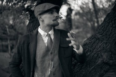 1920 'lerden kalma düz şapkalı bir İngiliz gangsterin portresi. Sokakta sigara içiyor...