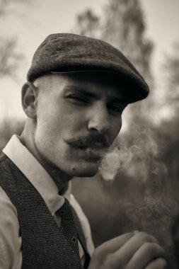 1920 'lerden kalma düz şapkalı bir İngiliz gangsterin portresi. Sokakta sigara içiyor...