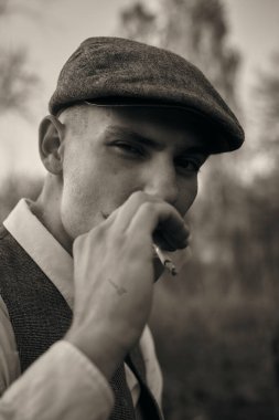 1920 'lerden kalma düz şapkalı bir İngiliz gangsterin portresi. Sokakta sigara içiyor...