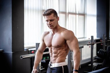Spor salonundaki kaslı adam. Çıplak gövde, Avrupa görünüşü. Fitness, sağlık, vücut geliştirme, erkek fiziği kategorisindeki erkekler..