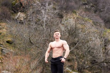 Çekici genç adam dışarıda kaslı gövde gösterisi yapıyor. Güzel vücut. Fitness ve yaşam tarzı konsepti. Basının telaffuz ettiği kaslar. Atletik fiziği.