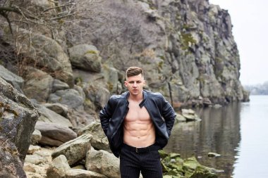 Çekici genç adam dışarıda kaslı gövde gösterisi yapıyor. Güzel vücut. Fitness ve yaşam tarzı konsepti. Basının telaffuz ettiği kaslar. Atletik fiziği.