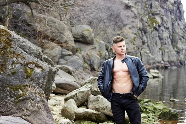 Çekici genç adam dışarıda kaslı gövde gösterisi yapıyor. Güzel vücut. Fitness ve yaşam tarzı konsepti. Basının telaffuz ettiği kaslar. Atletik fiziği.