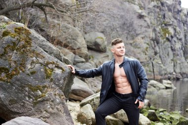 Çekici genç adam dışarıda kaslı gövde gösterisi yapıyor. Güzel vücut. Fitness ve yaşam tarzı konsepti. Basının telaffuz ettiği kaslar. Atletik fiziği.