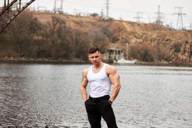 Çekici genç adam dışarıda kaslı gövde gösterisi yapıyor. Güzel vücut. Fitness ve yaşam tarzı konsepti. Basının telaffuz ettiği kaslar. Atletik fiziği.