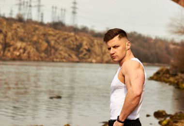 Çekici genç adam dışarıda kaslı gövde gösterisi yapıyor. Güzel vücut. Fitness ve yaşam tarzı konsepti. Basının telaffuz ettiği kaslar. Atletik fiziği.