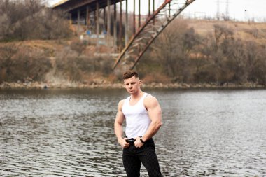 Çekici genç adam dışarıda kaslı gövde gösterisi yapıyor. Güzel vücut. Fitness ve yaşam tarzı konsepti. Basının telaffuz ettiği kaslar. Atletik fiziği.