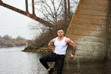 Çekici genç adam dışarıda kaslı gövde gösterisi yapıyor. Güzel vücut. Fitness ve yaşam tarzı konsepti. Basının telaffuz ettiği kaslar. Atletik fiziği.