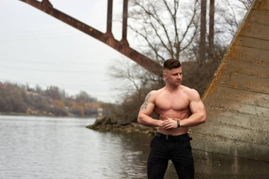 Çekici genç adam dışarıda kaslı gövde gösterisi yapıyor. Güzel vücut. Fitness ve yaşam tarzı konsepti. Basının telaffuz ettiği kaslar. Atletik fiziği.