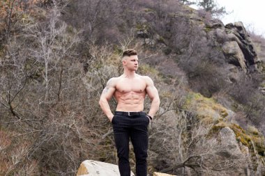 Çekici genç adam dışarıda kaslı gövde gösterisi yapıyor. Güzel vücut. Fitness ve yaşam tarzı konsepti. Basının telaffuz ettiği kaslar. Atletik fiziği.