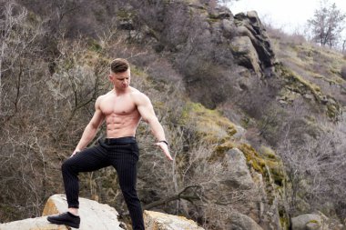 Çekici genç adam dışarıda kaslı gövde gösterisi yapıyor. Güzel vücut. Fitness ve yaşam tarzı konsepti. Basının telaffuz ettiği kaslar. Atletik fiziği.