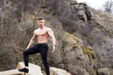 Çekici genç adam dışarıda kaslı gövde gösterisi yapıyor. Güzel vücut. Fitness ve yaşam tarzı konsepti. Basının telaffuz ettiği kaslar. Atletik fiziği.