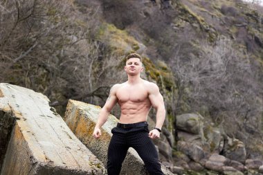 Çekici genç adam dışarıda kaslı gövde gösterisi yapıyor. Güzel vücut. Fitness ve yaşam tarzı konsepti. Basının telaffuz ettiği kaslar. Atletik fiziği.