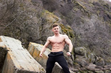 Çekici genç adam dışarıda kaslı gövde gösterisi yapıyor. Güzel vücut. Fitness ve yaşam tarzı konsepti. Basının telaffuz ettiği kaslar. Atletik fiziği.