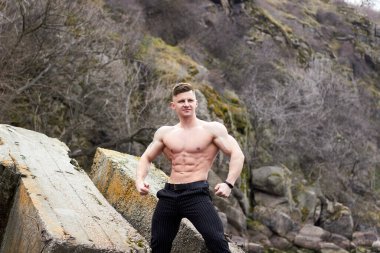 Çekici genç adam dışarıda kaslı gövde gösterisi yapıyor. Güzel vücut. Fitness ve yaşam tarzı konsepti. Basının telaffuz ettiği kaslar. Atletik fiziği.