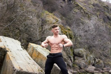 Çekici genç adam dışarıda kaslı gövde gösterisi yapıyor. Güzel vücut. Fitness ve yaşam tarzı konsepti. Basının telaffuz ettiği kaslar. Atletik fiziği.