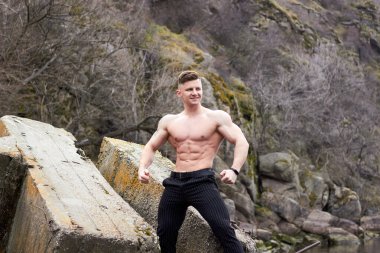 Çekici genç adam dışarıda kaslı gövde gösterisi yapıyor. Güzel vücut. Fitness ve yaşam tarzı konsepti. Basının telaffuz ettiği kaslar. Atletik fiziği.