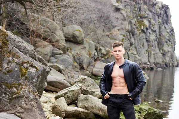 Çekici genç adam dışarıda kaslı gövde gösterisi yapıyor. Güzel vücut. Fitness ve yaşam tarzı konsepti. Basının telaffuz ettiği kaslar. Atletik fiziği.