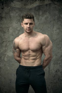 Beton duvarda poz veren yakışıklı kaslı adam. Fitness konsepti, vücut geliştirme, sağlık, yaşam tarzı. Fitness fitness modelinin portresi.
