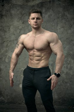 Beton duvarda poz veren yakışıklı kaslı adam. Fitness konsepti, vücut geliştirme, sağlık, yaşam tarzı. Fitness fitness modelinin portresi.