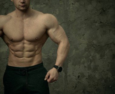 Beton duvarda poz veren yakışıklı kaslı adam. Fitness konsepti, vücut geliştirme, sağlık, yaşam tarzı. Fitness fitness modelinin portresi.