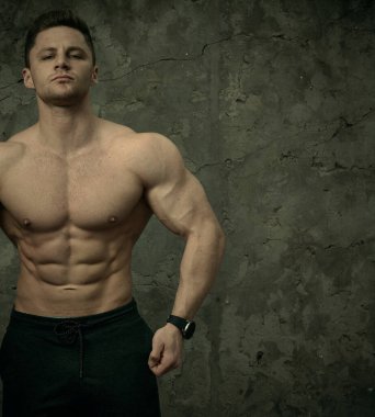 Beton duvarda poz veren yakışıklı kaslı adam. Fitness konsepti, vücut geliştirme, sağlık, yaşam tarzı. Fitness fitness modelinin portresi.