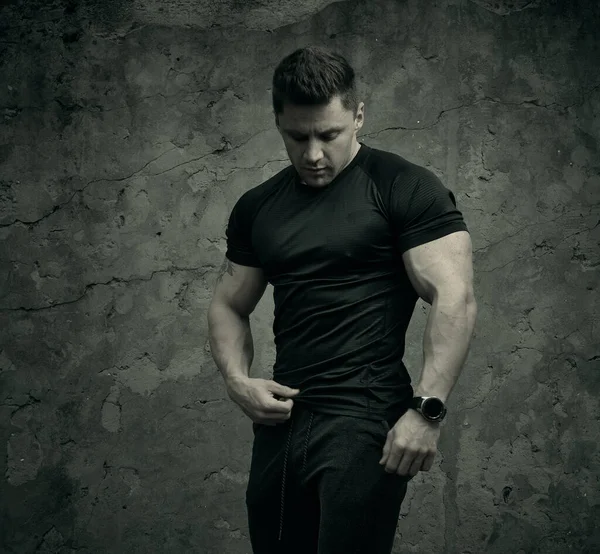 Spor tişörtlü bir adamın çekici atletik portresi. Bir fitness modelinin güzel portresi. Fitness, sağlık, yaşam tarzı kavramı. Spor kıyafetleri..