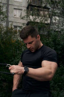 Atletik çekici adam dışarıda antrenman yapıyor. Spor, sağlık, fitness konsepti. Spor tişörtlü genç adam..