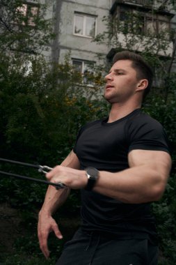 Atletik çekici adam dışarıda antrenman yapıyor. Spor, sağlık, fitness konsepti. Spor tişörtlü genç adam..