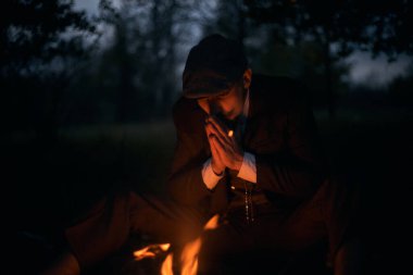 Geceleri şöminenin başında oturan bir adamın portresi. Sinematik klasik fotoğraf. 1920 'lerden kalma düz şapkalı bir İngiliz portresi..