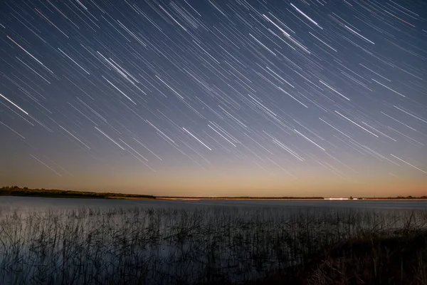 手前の湖と芝生の上のトラックの形で星と夜空の美しい景色 — ストック写真