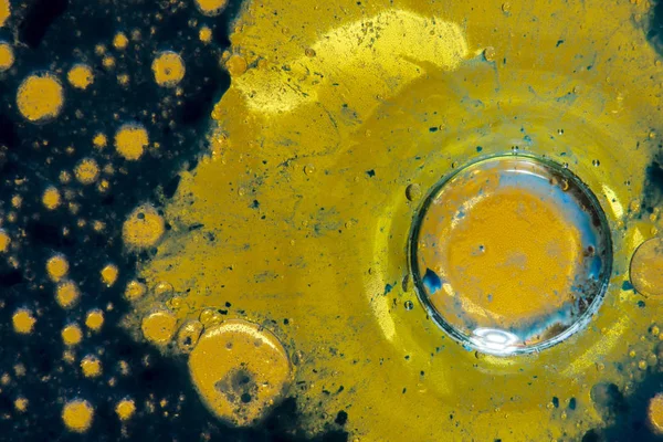blue and yellow abstract background with oil bubbles on colored water