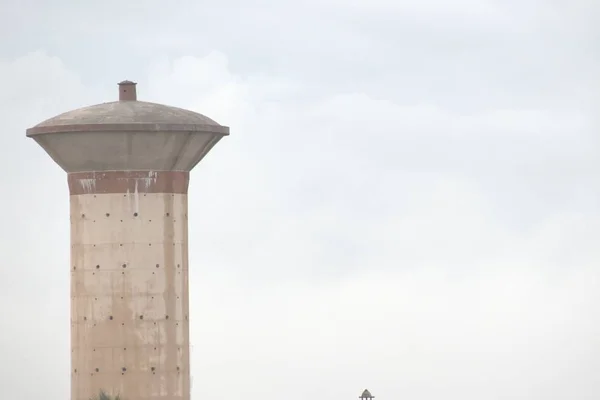 Una vista superior del tanque de almacenamiento de agua de hormigón de cemento, que suministra agua a la población rural viva. con el fondo del cielo —  Fotos de Stock