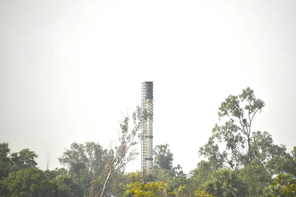 烟斗在绿树上飘扬，工厂烟囱冒出的烟污染空气. — 图库照片