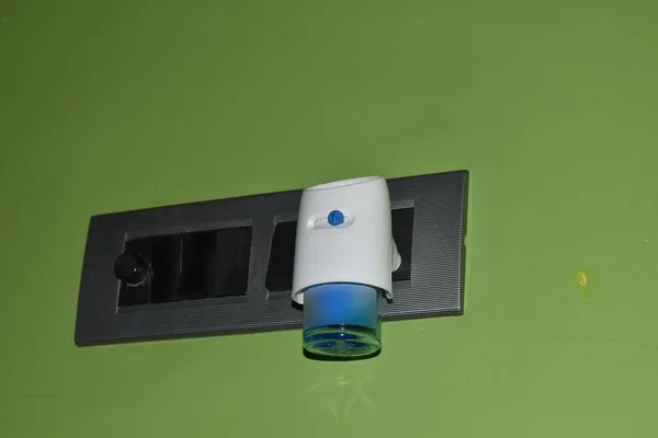 electric anti-mosquito fumigator in the wall socket. close up view. background of colored wall