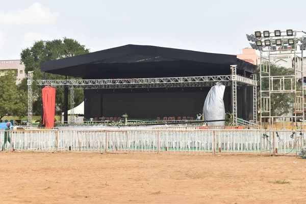 İnsanların olmadığı, odaklı ışıkların ve boş sandalyelerin olduğu bir açık hava sahnesi..