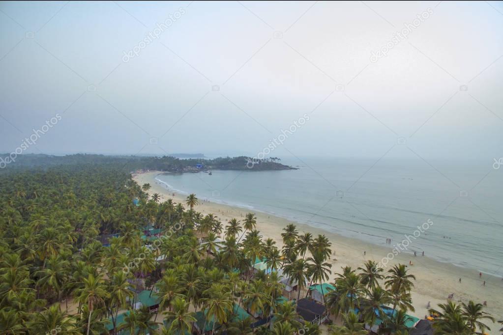 Aerial view of beautiful coastline of Indian ocean with tropical forest, sandy beach and calm blue water in Goa