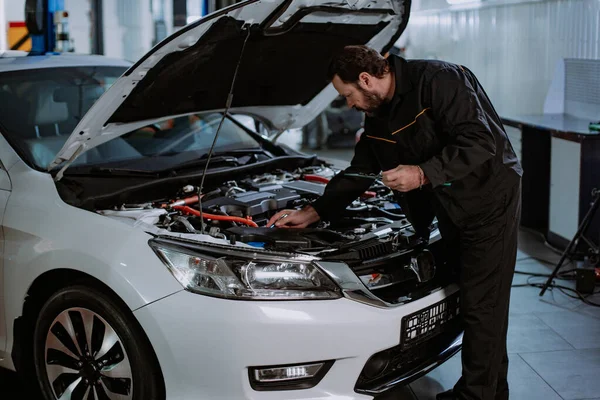 Good looking man mechanic in front of the camera showing a big like while working on a car in a modern auto service center — Stock Photo, Image