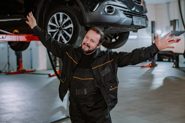 Um mecânico maduro está muito feliz, feliz que ele tenha concluído o reparo do carro — Fotografia de Stock