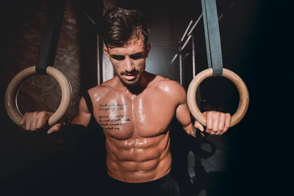 Voor de camera goed uitziende man in een donkere cross fitness klasse hij zijn harde en intense training af — Stockfoto