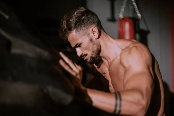 Concentrated strong athletic man lift up the big tire in cross fitness class — Stock Photo, Image