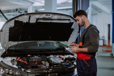 Tamirci üniformalı adam arabanın sorununu modern servis merkezindeki bir haritaya yazmış.
