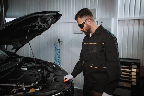 Jóképű szerelő, aki a motorját nézi egy autószervizben. — Stock Fotó