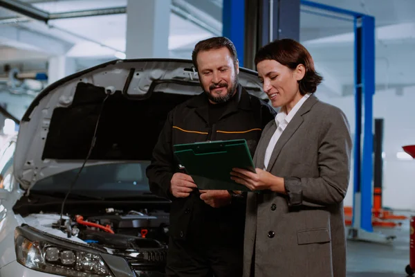 Service auto center monteur hebben een gesprek met de klant vrouw ze toont ondertekende documenten — Stockfoto